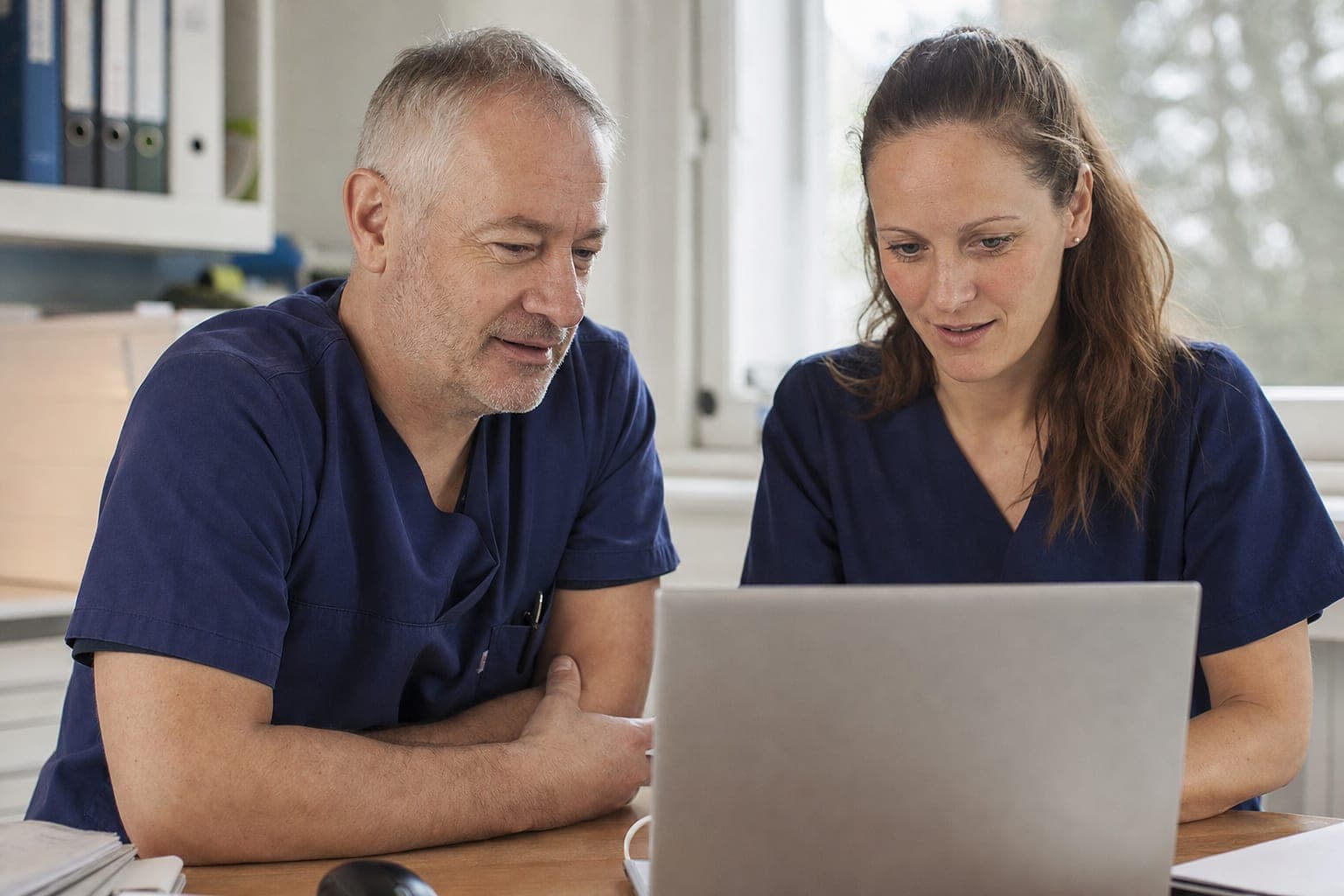 Zwei Personen im Büro besprechen am Laptop die offene Stelle
